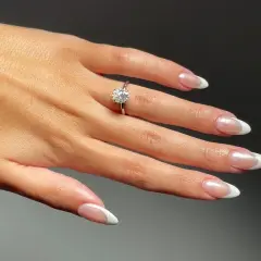 Dłoń z pierścionkiem zaręczynowym i idealnymi paznokciami na zaręczyny. Klasyczny french manicure podkreśla blask kamienia.