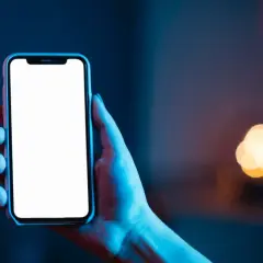 Dłoń trzyma smartfon z pustym ekranem **AMOLED**, otoczony niebieskim i czerwonym światłem.