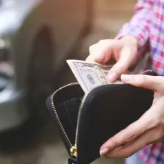 Ręce wyciągają banknot 50 dolarów z portfela, przygotowując się do kupna samochodu od osoby prywatnej.