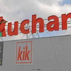 Duże czerwone logo Auchan z ptaszkiem, poniżej banery sklepów Floraria Rhapsody i Kik. Aplikacja Auchan ułatwia zakupy.
