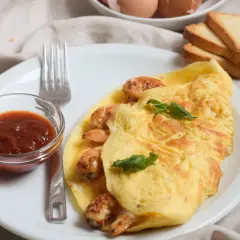 Tortilla de gambas dorada y jugosa, servida con salsa y tostadas. Un desayuno perfecto.