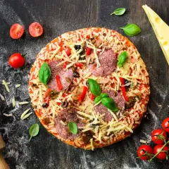 Gotowa pizza z salami, serem i warzywami, obok wałek, ser i pomidorki. Idealna do przygotowania z odpowiednią mąką do pizzy.