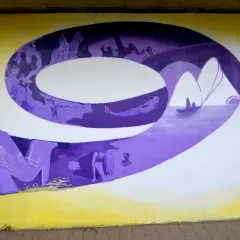 Graffiti-Wandmalerei mit lila 3D-Buchstaben und Szenen wie Reiter, Meerjungfrau und Boot.