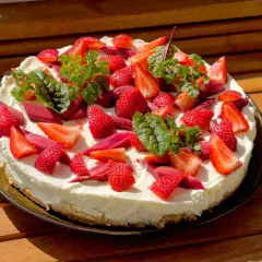 Ein köstlicher Erdbeer Rhabarber Kuchen mit frischen Früchten und Kräutern, bereit zum Genießen.