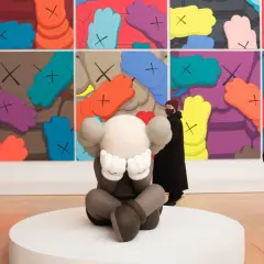 A KAWS sculpture sits before a vibrant mural, inspiring KAWS painting ideas. Visitors admire the art.
