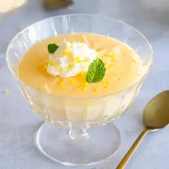 Cremiges Lemon Curd Dessert im Glas, garniert mit Sahne, Minze und Zitronenschale. Perfekt für ein einfaches Lemon Curd Rezept.