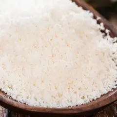 Cuchara de madera con rallado fino de parmesano vegano, listo para espolvorear sobre tu plato favorito.