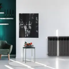 Nowoczesny grzejnik stalowy czy aluminiowy? W stylowym salonie z zieloną kanapą i abstrakcyjnym obrazem, ciemnoszary grzejnik dodaje elegancji.
