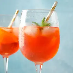 Zwei erfrischende Aperol Spritz mit Eis und Minze, bereit für einen sonnigen Nachmittag.