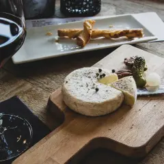 Verre de vin rouge avec un plateau de fromage, cornichons et noix. Un délice pour accompagner une dégustation de vin rouge avec charcuterie et fromage.