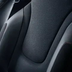 Sièges de voiture en cuir noir et matière alcantara, avec surpiqûres rouges contrastantes.