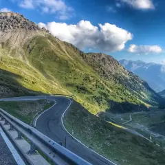 Kręta, górska stelvio droga wije się przez zielone zbocza Alp, prowadząc w głąb doliny.