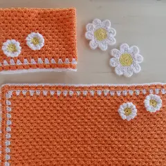 Tovagliette uncinetto schemi gratis: un set arancione con fiori bianchi e gialli, perfetto per decorare la tavola.