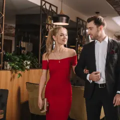 Para, ubrana w czerwoną sukienkę, i mężczyzna w garniturze, idealnie wpisują się w dress code cocktail.