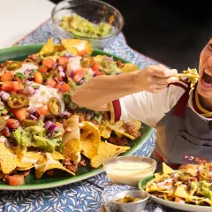 Una mujer disfruta de unos deliciosos nachos tex mex, cargados de carne, guacamole, queso y jalapeños.