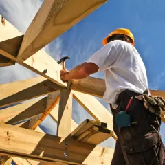 Cieszący się słońcem cieśla buduje dach, używając tradycyjne połączenia ciesielskie.