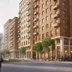 En modern stadsbild i Sverige med tegelbyggnader, balkonger och grönska. En kvinna med en väska går längs en stenlagd gata.