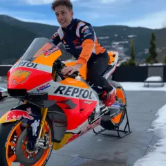 Piloto de Honda MotoGP con su moto Repsol, listo para la temporada, con montañas nevadas de fondo.
