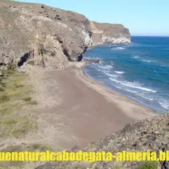 Playa virgen de cala principe, Cabo de Gata, con acantilados rocosos y mar azul.