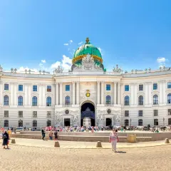 Majestatyczny pałac Sisi w Wiedniu, z zieloną kopułą i tłumem turystów na placu.