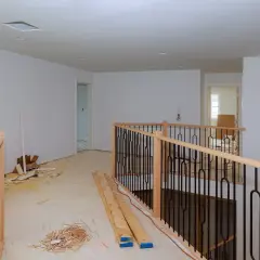 Drewniana balustrada na balkonie, gotowa do montażu. Widać materiały budowlane i okno.
