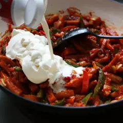 Gräddig korvgryta recept i pannan. Korv, paprika och lök blandas med en stor klick grädde.
