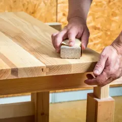 Mains poncent un plan de travail en bois avec une cale à poncer pour une finition lisse.