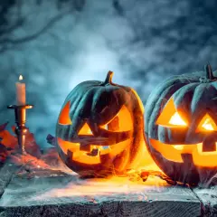 Gruselige Kürbisse mit Kerzenlicht und Herbstlaub. Ein Hauch von Mysterium, das an den Halloween Ursprung in Deutschland erinnert.