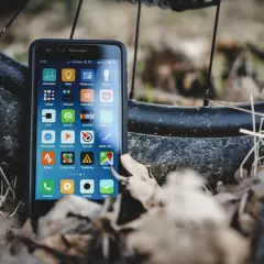 Szukasz alternatywy dla Endomondo za darmo? Smartfon z aplikacjami do śledzenia aktywności, jak Strava czy Locus Map, leży obok opony rowerowej.