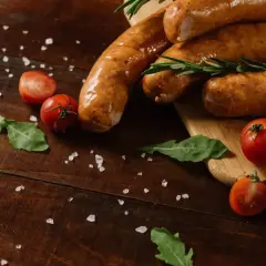 Kiełbasa śląska przepis: soczyste kiełbaski, pomidorki koktajlowe, rukola i gruboziarnista sól na drewnianym blacie.
