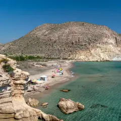 La cala del Peñón Blanco, con su arena dorada y aguas cristalinas, invita a disfrutar del sol bajo un cielo azul.