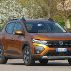 Dacia Sandero Stepway arancione in movimento, con alberi fioriti sullo sfondo. Nonostante i suoi pregi, alcuni difetti Dacia Sandero Stepway sono noti.