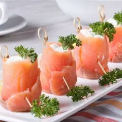 Rotolini di salmone affumicato con formaggio cremoso e prezzemolo, perfetti per ricette fredde.