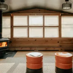 Une cheminée dans une véranda confortable, avec des flammes vives réchauffant la pièce. Deux poufs orange vif invitent à la détente.