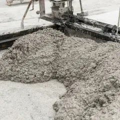 Świeży beton wylewany z betoniarki. Z czego jest cement? Z wapienia i gliny, które po wypaleniu i zmieleniu tworzą spoiwo.