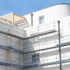 Immeuble blanc en construction avec échafaudages. Idéal pour un modèle lettre bailleur sociaux pour travaux.