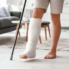 Mężczyzna z kulami pod pachą, z nogą w gipsie, walczy ze sztywnym stawem skokowym po złamaniu.