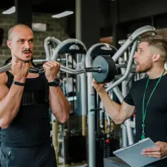 Trener instruuje klienta, jak wykonać ćwiczenie. Czy to superseria? Dowiedz się, co to jest i jak może pomóc w treningu.