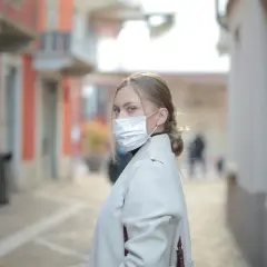 Kobieta w masce na twarzy na ulicy, zastanawia się, ile można chorować w Polsce.