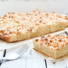 Ein Stück saftiger low carb streusel Kuchen mit Butter und einer Gabel auf einem Holztisch.
