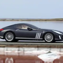 Elegancki, ciemnoszary Peugeot 907 sunie po drodze nad różowym jeziorem.