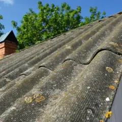 Stary eternit na dachu, porośnięty mchem i porostami. Zastanawiasz się, co zrobić z eternitem zdjętym z dachu? Pamiętaj o bezpiecznym usuwaniu i utylizacji.