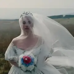 Panna młoda w welonie i koronie na tle wietrznego krajobrazu. Jak w Wichrowych Wzgórzach, jej los splata się z dziką naturą.
