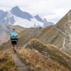 Wędrowiec na szlaku w **Alpach Austriackich**, podziwiający jedne z najpiękniejszych miejsc z lodowcem w tle.