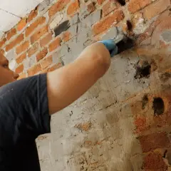 Mann repariert Ziegelwand, um Sickerwasser zu stoppen.
