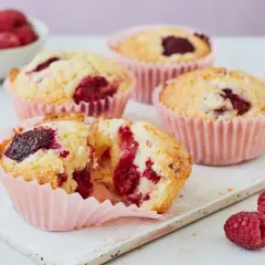 Saftige Himbeer Muffins in rosa Förmchen, mit frischen Himbeeren garniert. Ein Genuss!