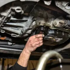 Mechanik sprawdza pękniętą miskę olejową, z której wycieka olej.