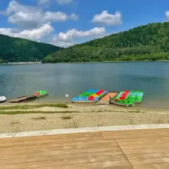 Kolorowe rowerki wodne i kajaki czekają nad spokojnym jeziorem w górach.