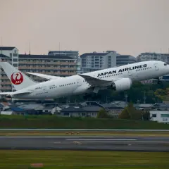 Samolot JAL Japan Airlines wznosi się nad miastem.