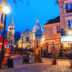 Montmartre di sera, un luogo magico dove uscire a Parigi. Artisti, caffè e la Basilica del Sacro Cuore illuminata.